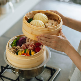 中華せいろを2段重ねて。1段目は真っ赤なトマト、黄色のズッキーニ、紫キャベツに、アスパラガス...と色とりどりの野菜と豚肉を入れています。上に重ねる2段目は、肉まんとシューマイ。