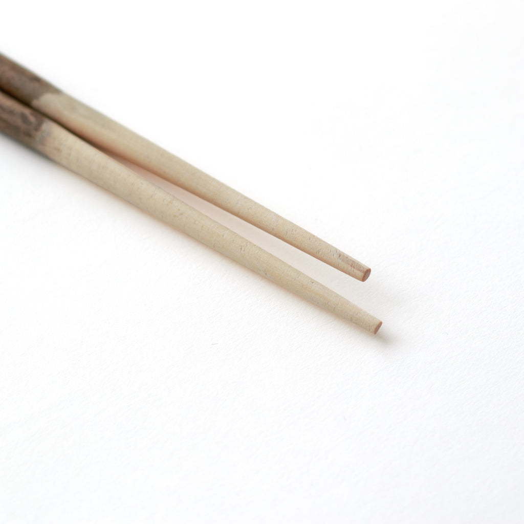 箸先。ラオスに自生するケームという木で作った箸。樹皮を残している部分と明るく白っぽい木肌のコントラストが個性的。